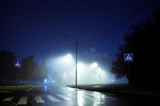 人行横道横穿雾气弥漫的空旷街道，夜幕降临，