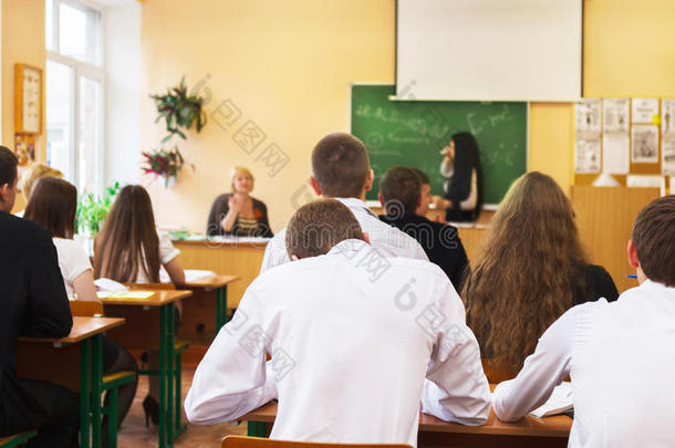 学生在课桌旁听女学生讲话的后视图