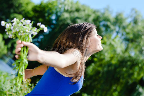 户外自由：美丽的年轻女人的肖像，享受阳光，快乐地微笑&拿着一束雏菊
