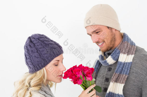 一对穿着温暖衣服手持鲜花的迷人情侣