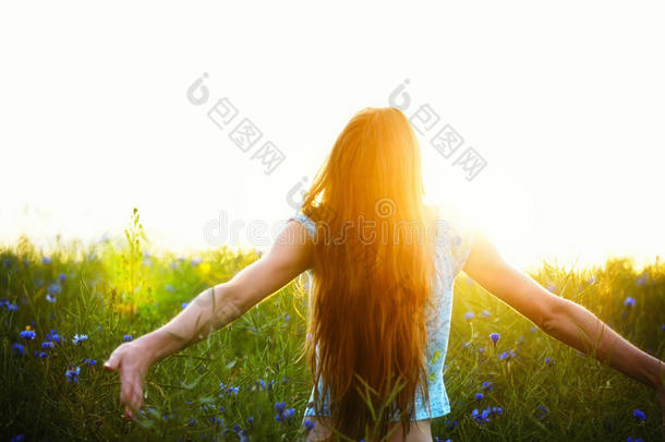 在油菜地里高举双臂享受阳光的年轻女子