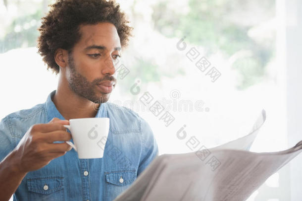 漫不经心的男人一边看报纸一边喝咖啡