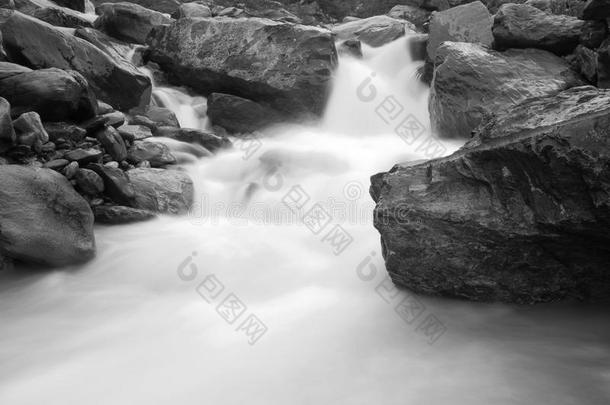 高山溪陡峭的石质河床。溪水的波浪模糊地流过巨石和石头，雨后水位很高