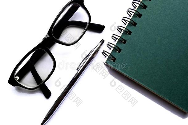 螺旋装订的笔记本，眼镜和笔在白纸上