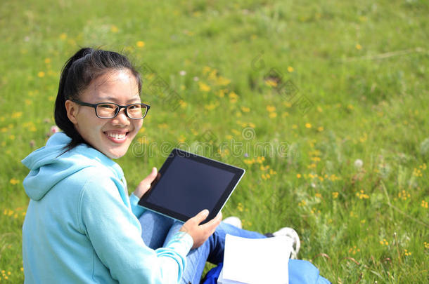 <strong>女大学生</strong>用平板电脑坐在草地上