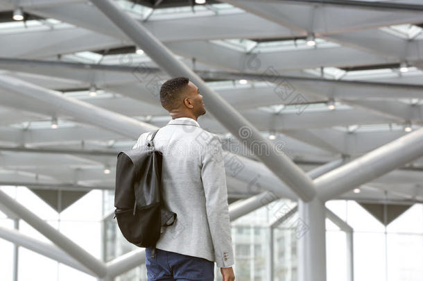 一个拿着包的黑人独自站在机场