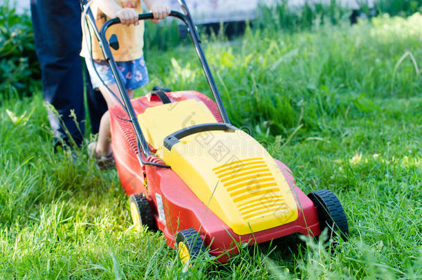 每一个小小的帮助都很重要：草坪修剪或草坪移动机操作或<strong>推动</strong>由小男孩或女孩和成人后面