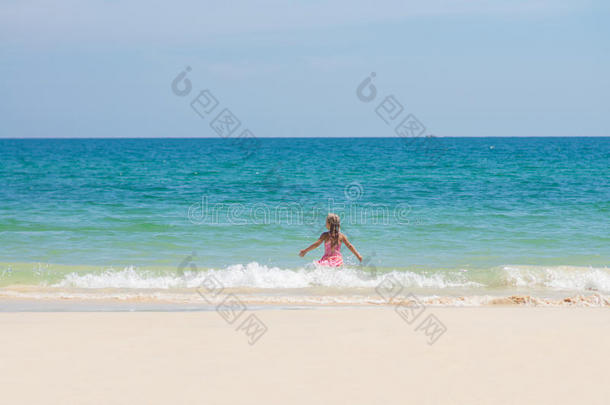 可爱的女孩穿着粉红色的游泳衣在海浪中<strong>奔向</strong>大海
