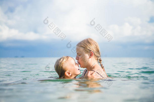 年轻的母女俩在热带海洋的小岛上游泳玩得很开心。互相拥抱