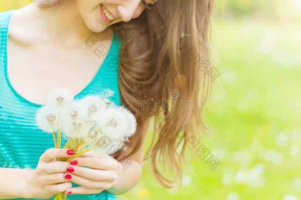 阳光明媚的一天，一个美丽快乐的女孩在公园里休息，手里拿着<strong>长长</strong>的蒲公英短裤和t恤
