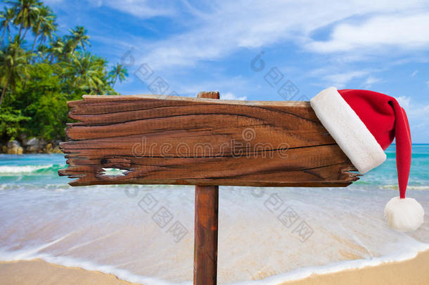 海滩圣诞概念。带圣诞老人帽的木制招牌。