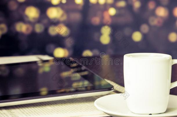 一杯咖啡放在靠近窗户的数码平板电脑前，复古风格