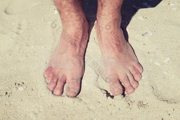 在一个阳光明媚的海滩上，男人光着脚在温暖的沙滩上度假。