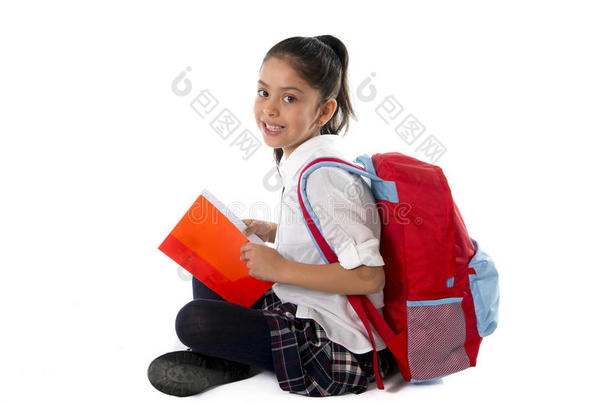 快乐的拉丁语学校小女孩笑着坐在地板上看<strong>课本</strong>或记事本