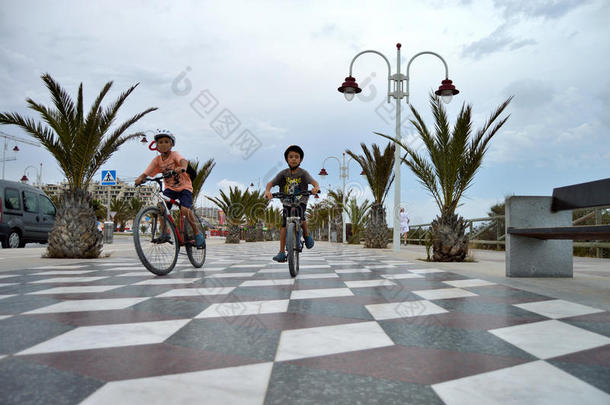 孩子们骑自行车在铺瓷砖的人行道上
