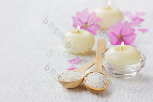 水疗组合，木勺海盐浴，粉色花朵，白色表面点燃蜡烛