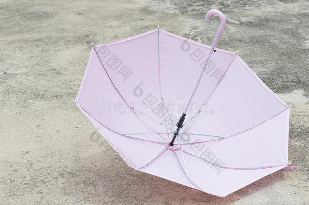 室外混凝土地板上的粉红色雨伞。