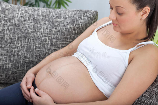 年轻漂亮的孕妇抚摸着她的大肚子