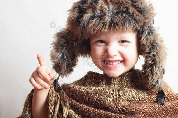 穿着皮草微笑的孩子帽子。时尚冬天风格。小有趣的孩子们情感