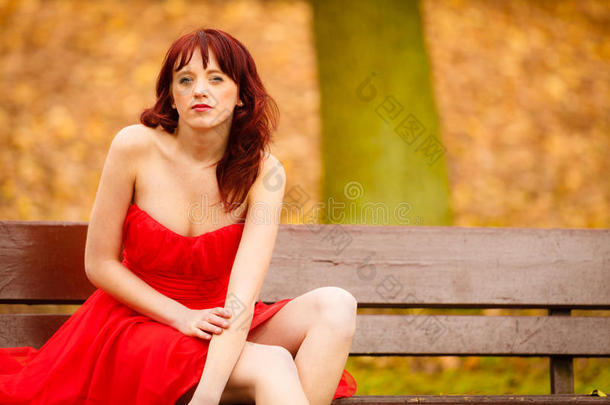 秋天<strong>公园里坐在</strong>长凳上的女人红裙子