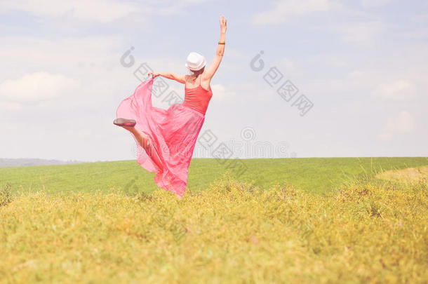户外欢乐时光：欢乐的画面优雅的金发红衣少女在绿色的夏日草地上快乐的跳舞复制空间