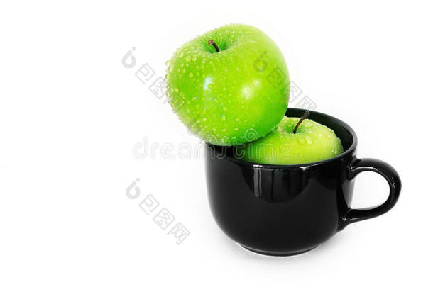 白色背景上黑色陶瓷杯中的新鲜绿色苹果