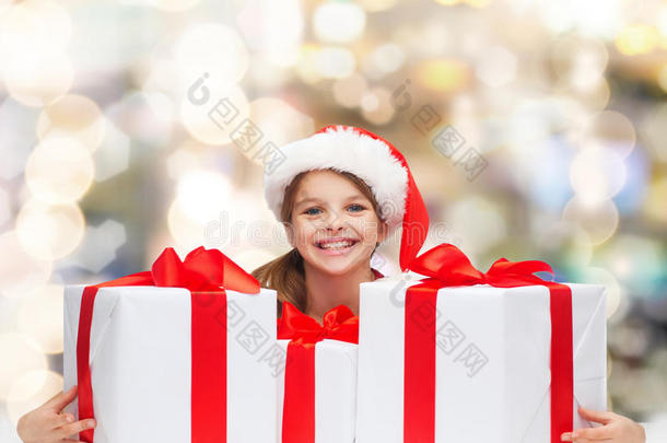 微笑的女孩戴着圣诞老人的帽子和礼品盒