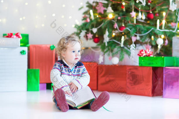 漂亮的小女孩在圣诞<strong>树下看书</strong>