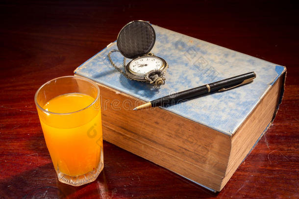 带笔、手表和橙汁的书。