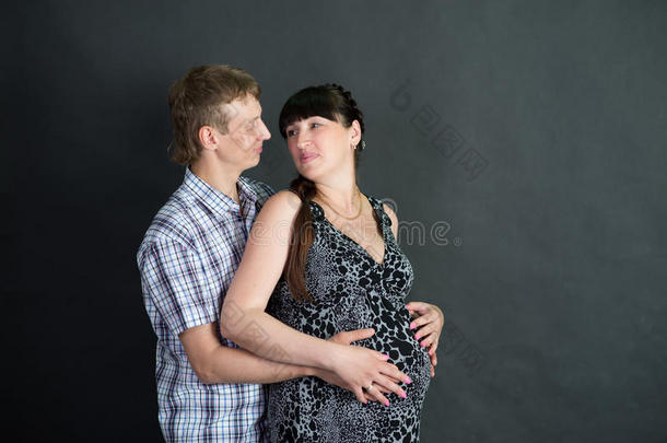 怀孕的黑发女人和丈夫在黑暗的背景。夫妇
