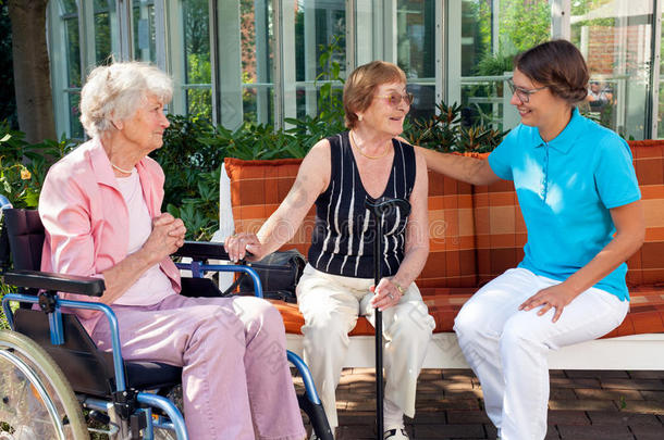 三个女人坐在花园的长凳上聊天。