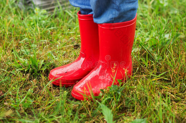 小脚穿着红靴子在绿草中行走的特写镜头