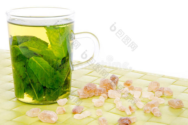 一杯薄荷茶和红糖放在绿色的垫子上