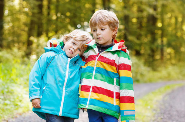两个穿着彩色雨衣和靴子的小男孩在散步
