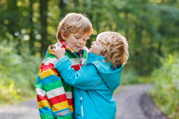 两个穿着彩色雨衣和靴子的小男孩在散步