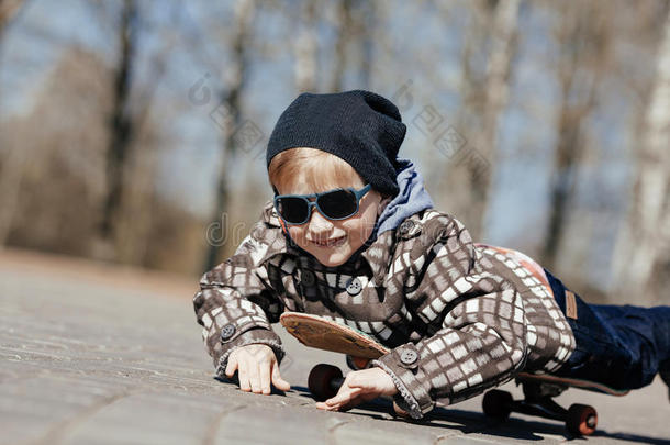 在街上玩滑板的小男孩