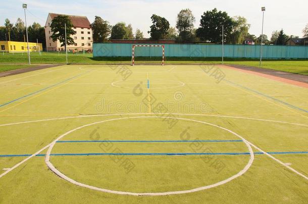 室外空荡荡的手球运动场，地面为塑料浅绿色表面。空门。