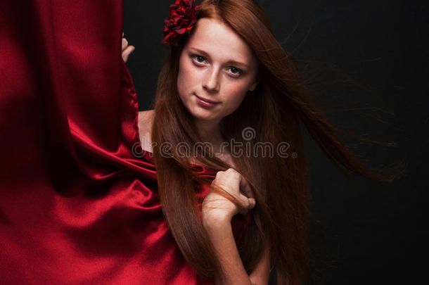美丽的红发女孩从一个红色剧院的后面向外张望