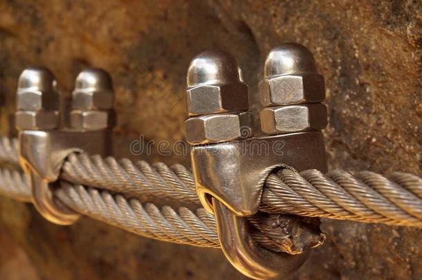 钢丝绳端部夹具详图。攀岩者用螺丝固定在滑轮上的铁绞绳，弹簧钩锚定在岩石上。