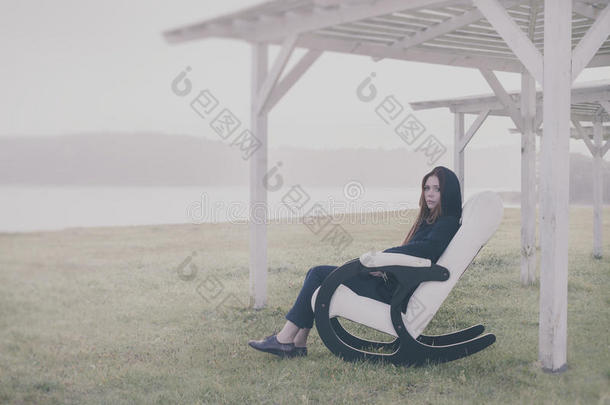 美丽快乐的女人早上在湖边的椅子上放松