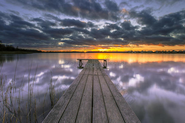 紫色的夕阳在宁静的湖面和木制的码头上
