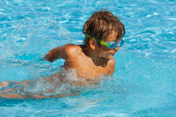 戴水上运动护目镜的小男孩在游泳池里游泳