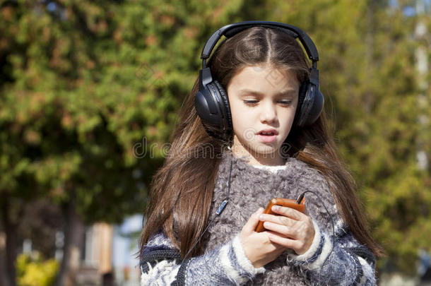 漂亮的小女孩戴着耳机听音乐