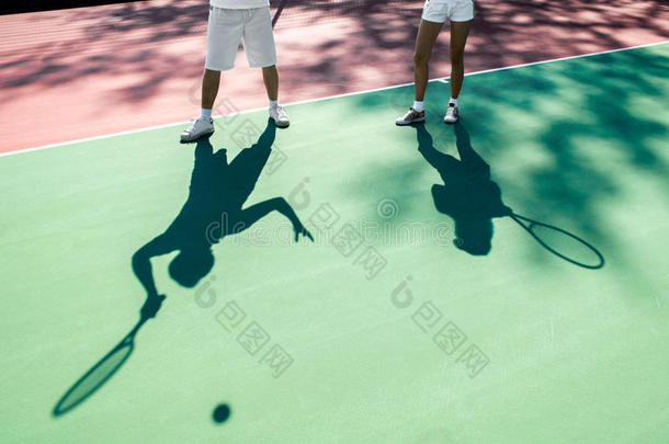 球员们在网球场上投下阴影