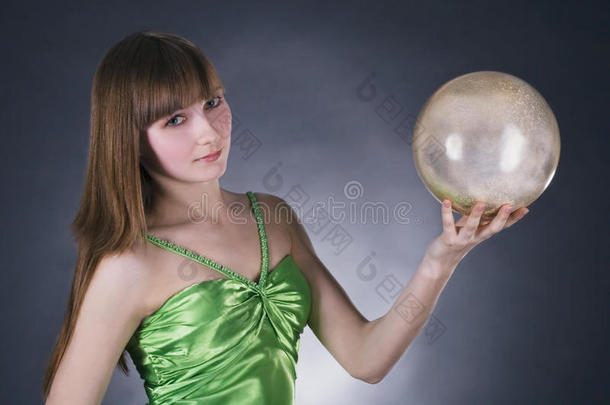 一位身穿绿色连衣裙，金色球体的女士
