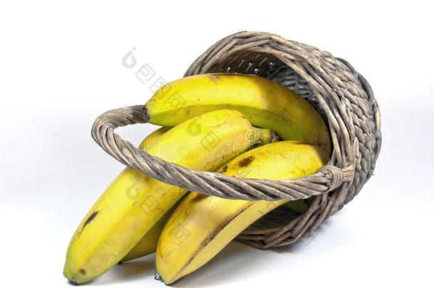 四个黄色的香蕉放在一个翻过来的柳条篮子里