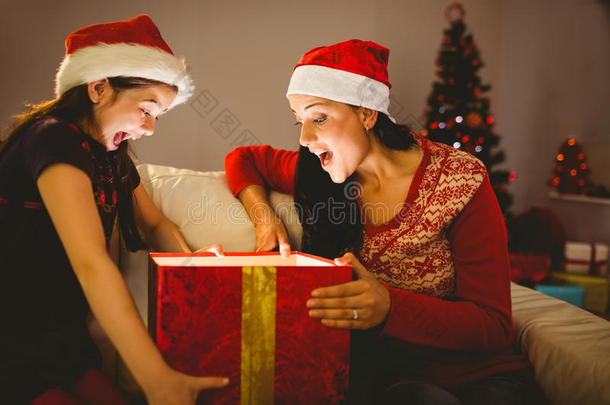 喜庆的母女俩打开一份闪闪发光的圣诞礼物