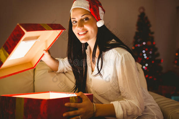 喜庆的黑发女人打开一个发光的圣诞礼物