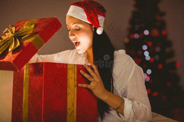 喜庆的黑发女人打开一个发光的圣诞礼物