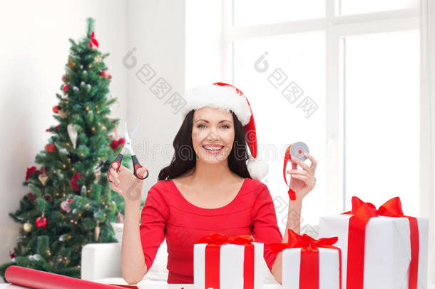 带着圣诞老人帽的微笑女人在<strong>打包礼物</strong>